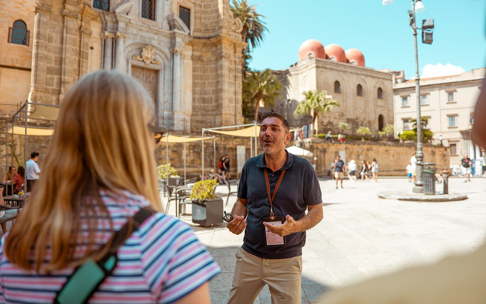 Tour guide leading a group in front of historic buildings in Palermo, Sicily.