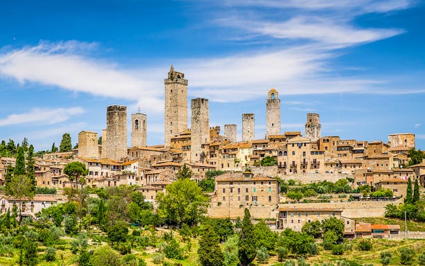 San Gimignano skyline with medieval towers under a blue sky, Tuscany, Italy.