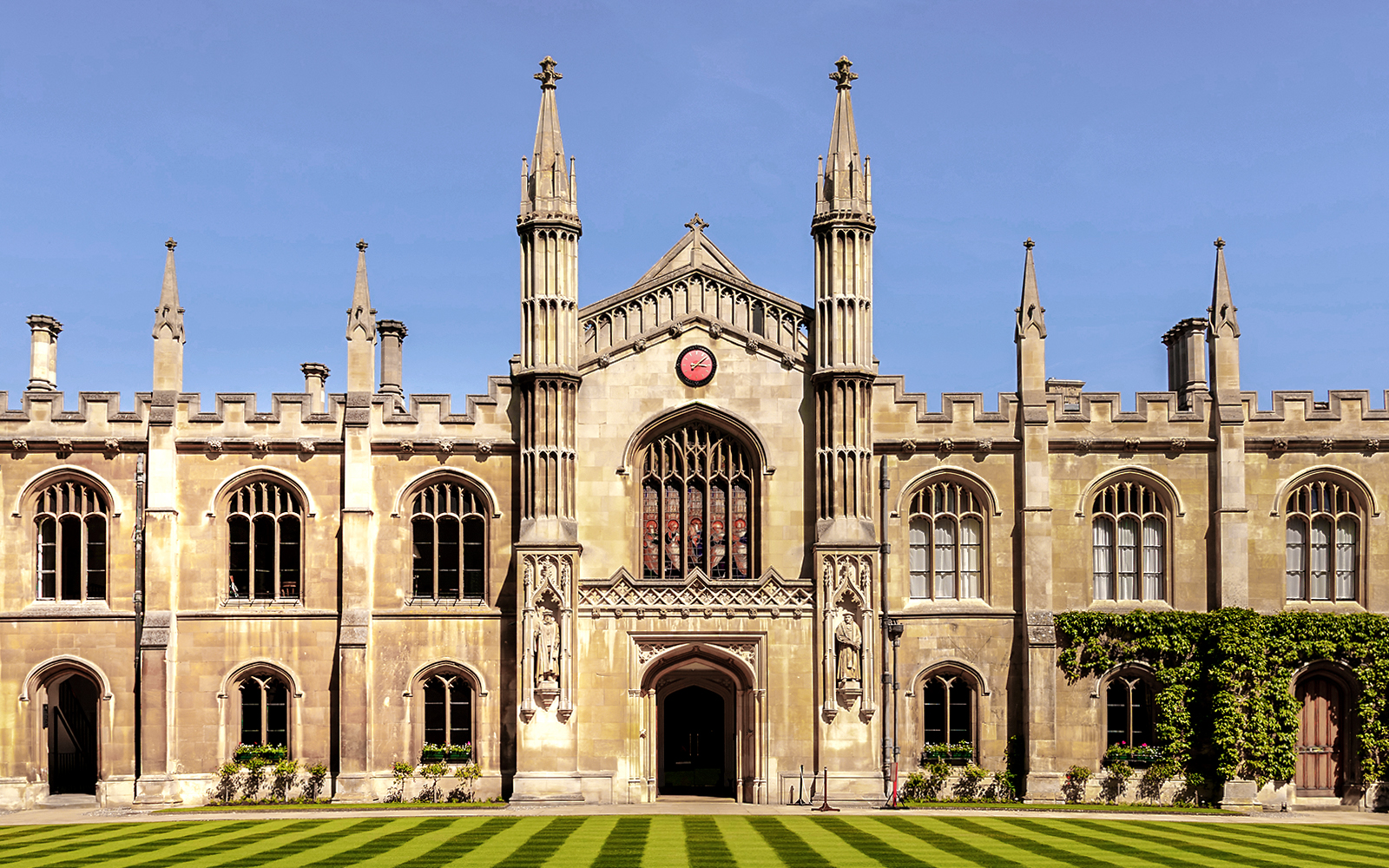University of Cambridge building with clock and spires against blue sky.