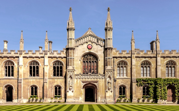 University of Cambridge building with clock and spires against blue sky.