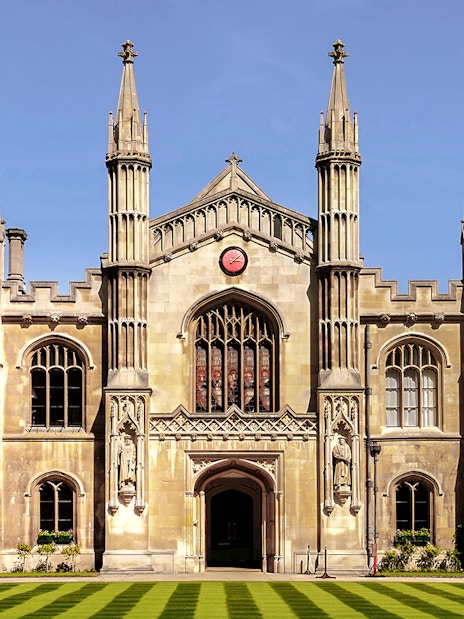 University of Cambridge building with clock and spires against blue sky.