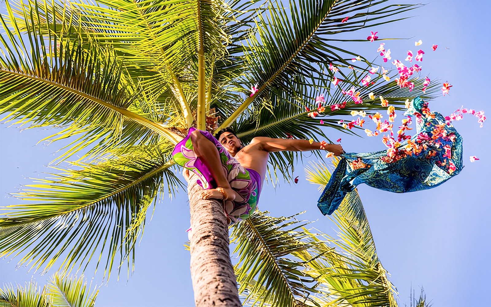 Man throwing flowers from a palm tree at Paradise Cove Luau, Hawaii.