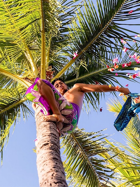 Man throwing flowers from a palm tree at Paradise Cove Luau, Hawaii.
