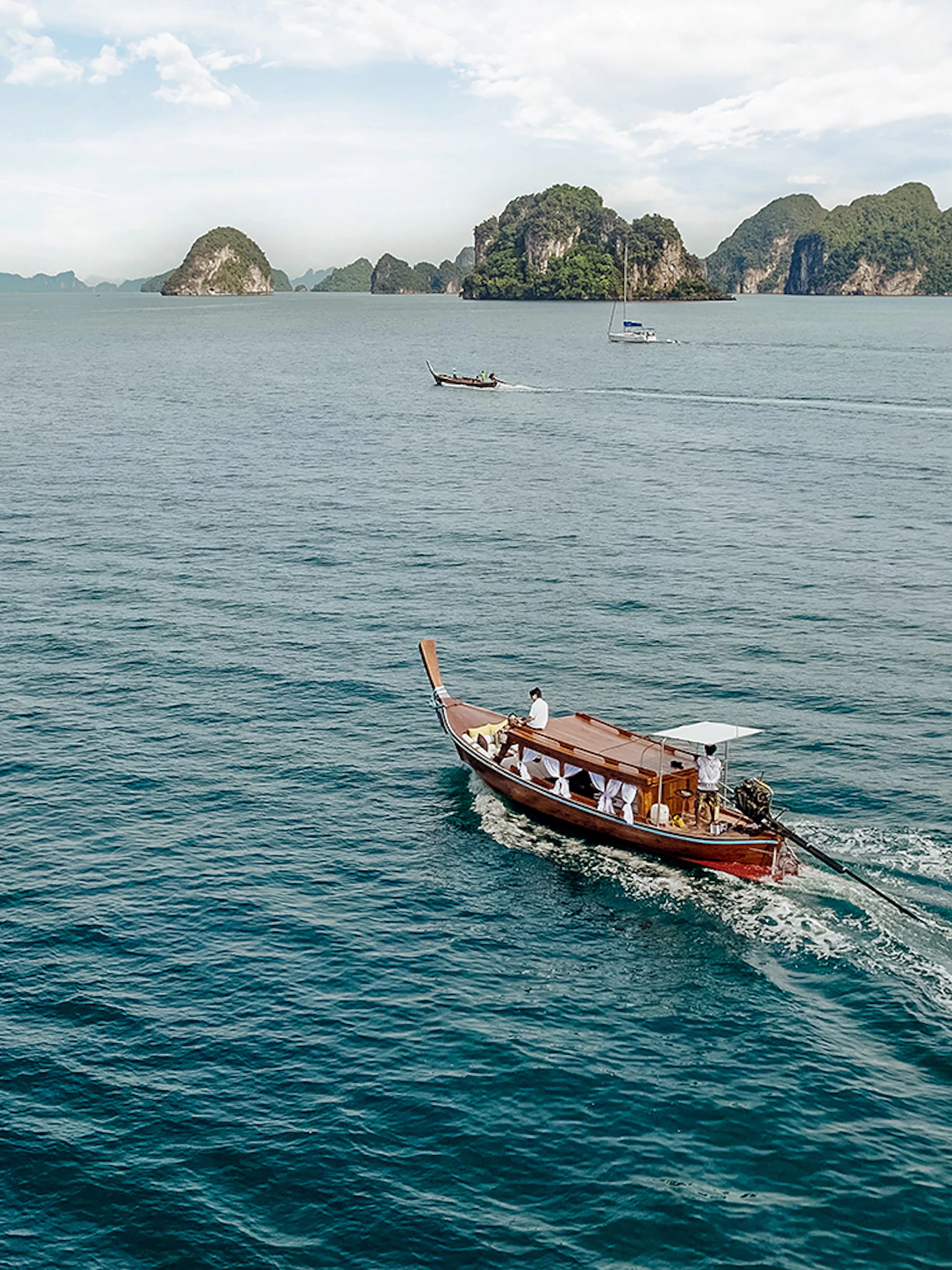 Longtail boat sailing near limestone islands in Krabi, Thailand.