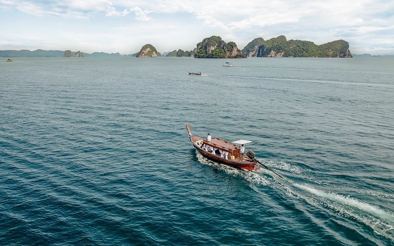 Longtail boat sailing near limestone islands in Krabi, Thailand.