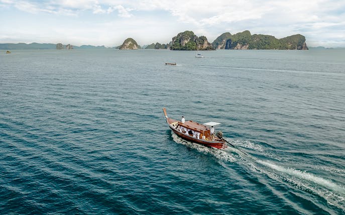 Longtail boat sailing near limestone islands in Krabi, Thailand.