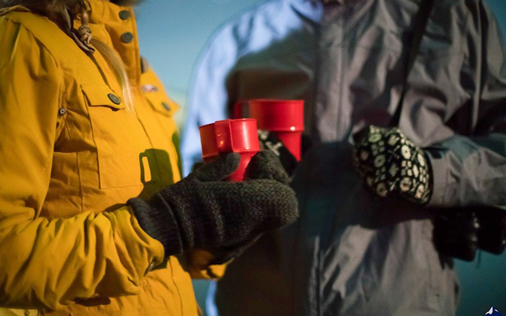 Guests holding red cups during Northern Lights jeep tour.
