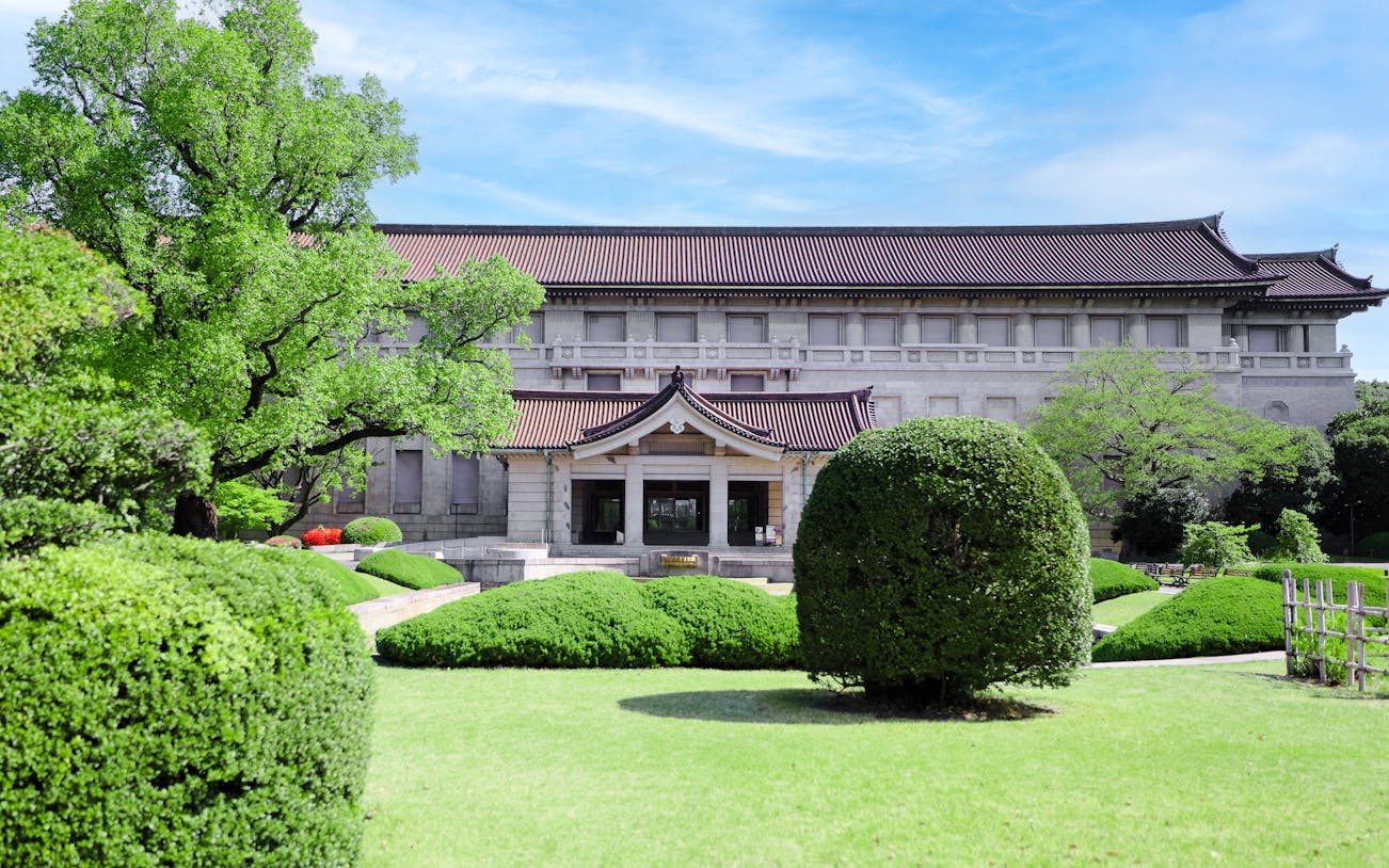 Tokyo National Museum main building with lush garden and traditional architecture.