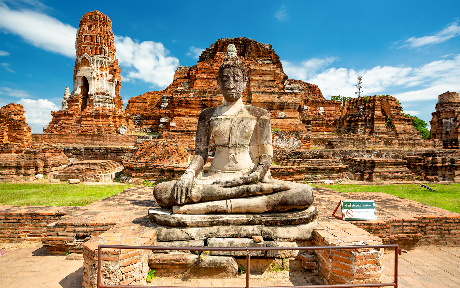 Seated Buddha statue at Ayutthaya Historical Park, Thailand, with ancient brick ruins.