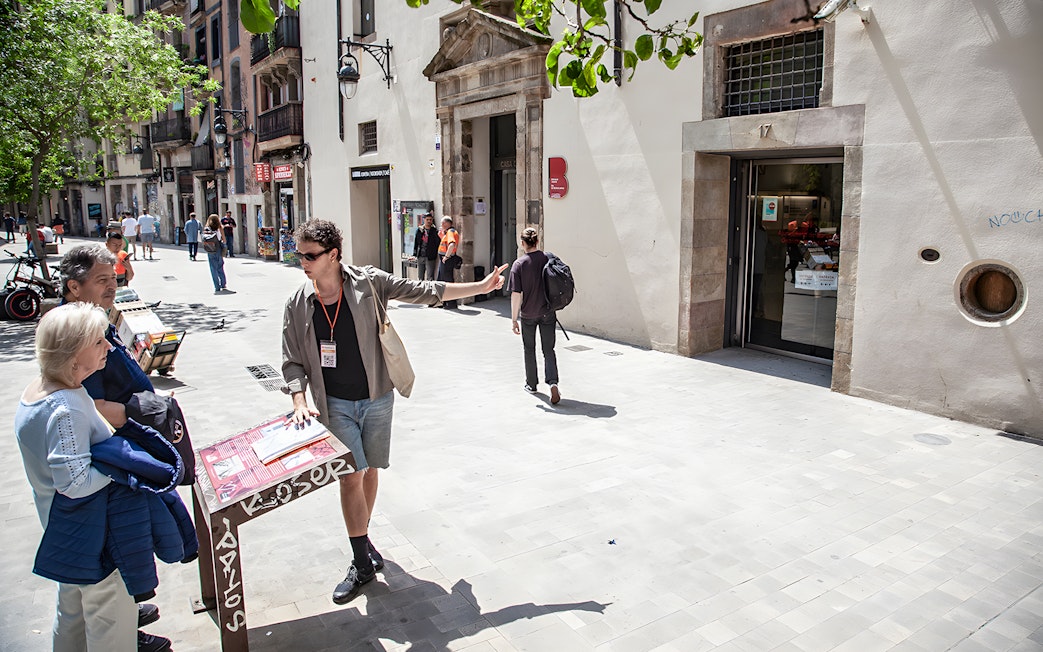 Tour guide explaining Raval's history to visitors on a street in Barcelona.