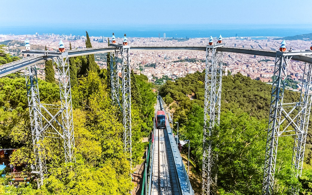 Funicular ascending Tibidabo Amusement Park with Barcelona cityscape in the background.