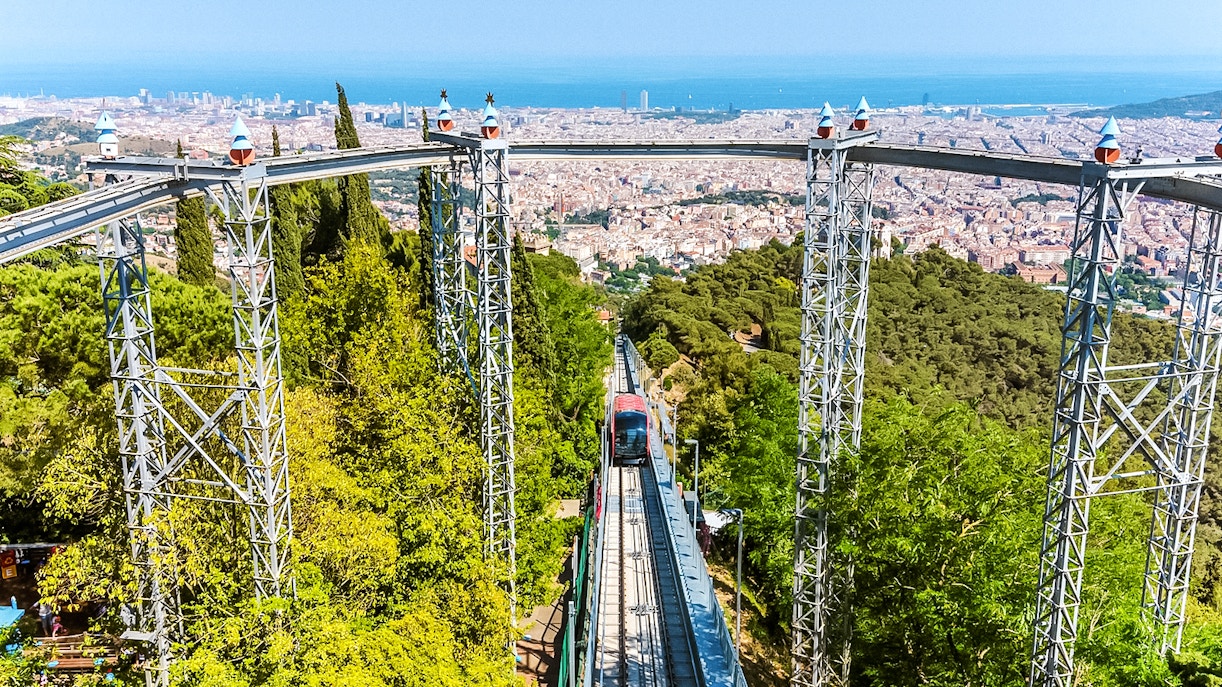 Funicular ascending Tibidabo Amusement Park with Barcelona cityscape in the background.