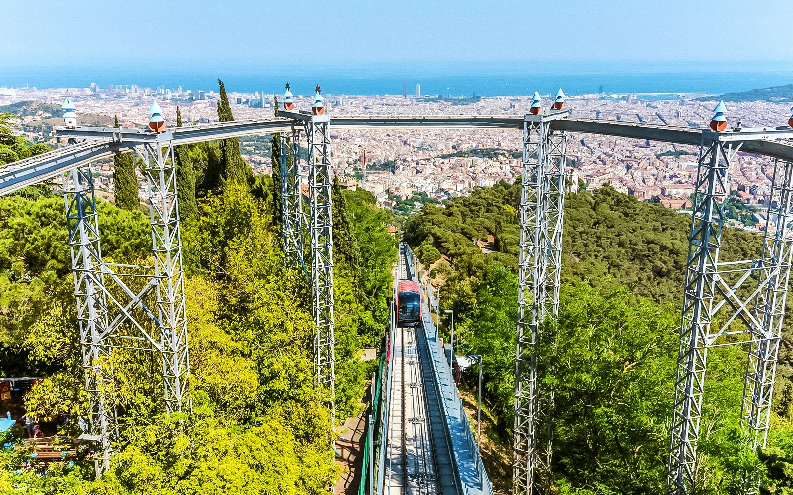 Funicular ascending Tibidabo Amusement Park with Barcelona cityscape in the background.