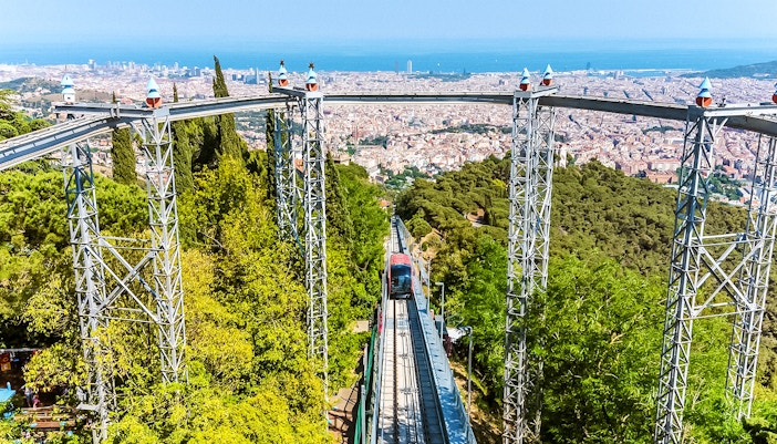 Funicular ascending Tibidabo Amusement Park with Barcelona cityscape in the background.