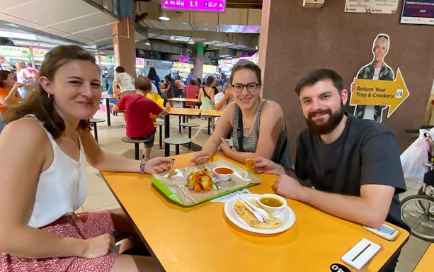 Visitors enjoying local dishes at a table in Little India Hawker Street, Singapore.