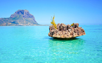Crystal rock formation in turquoise waters with Le Morne Brabant in the background, Mauritius.