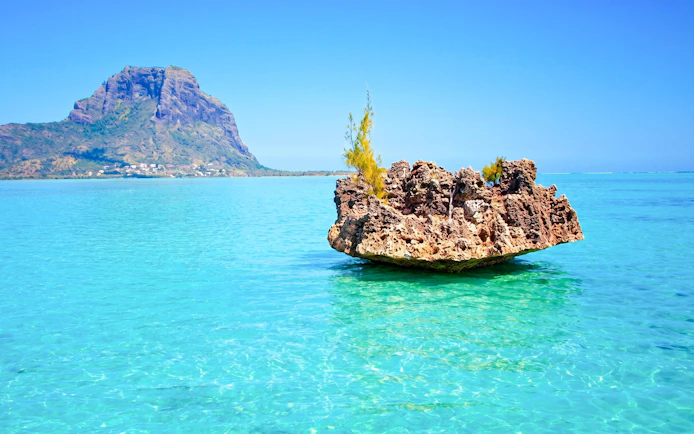 Crystal rock formation in turquoise waters with Le Morne Brabant in the background, Mauritius.