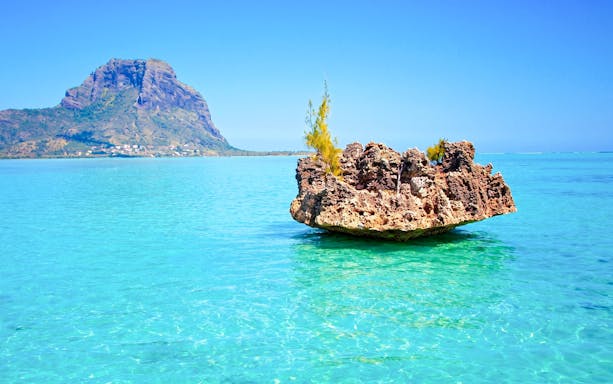 Crystal rock formation in turquoise waters with Le Morne Brabant in the background, Mauritius.