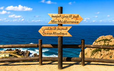 Sign pointing to Atlantic Ocean and Mediterranean Sea near coastline.