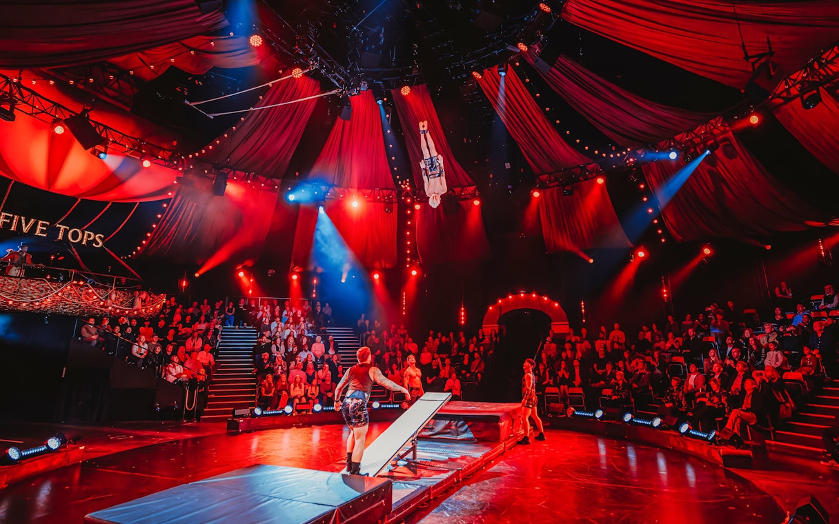 Acrobat performing mid-air flip during Come Alive Westend stage show.