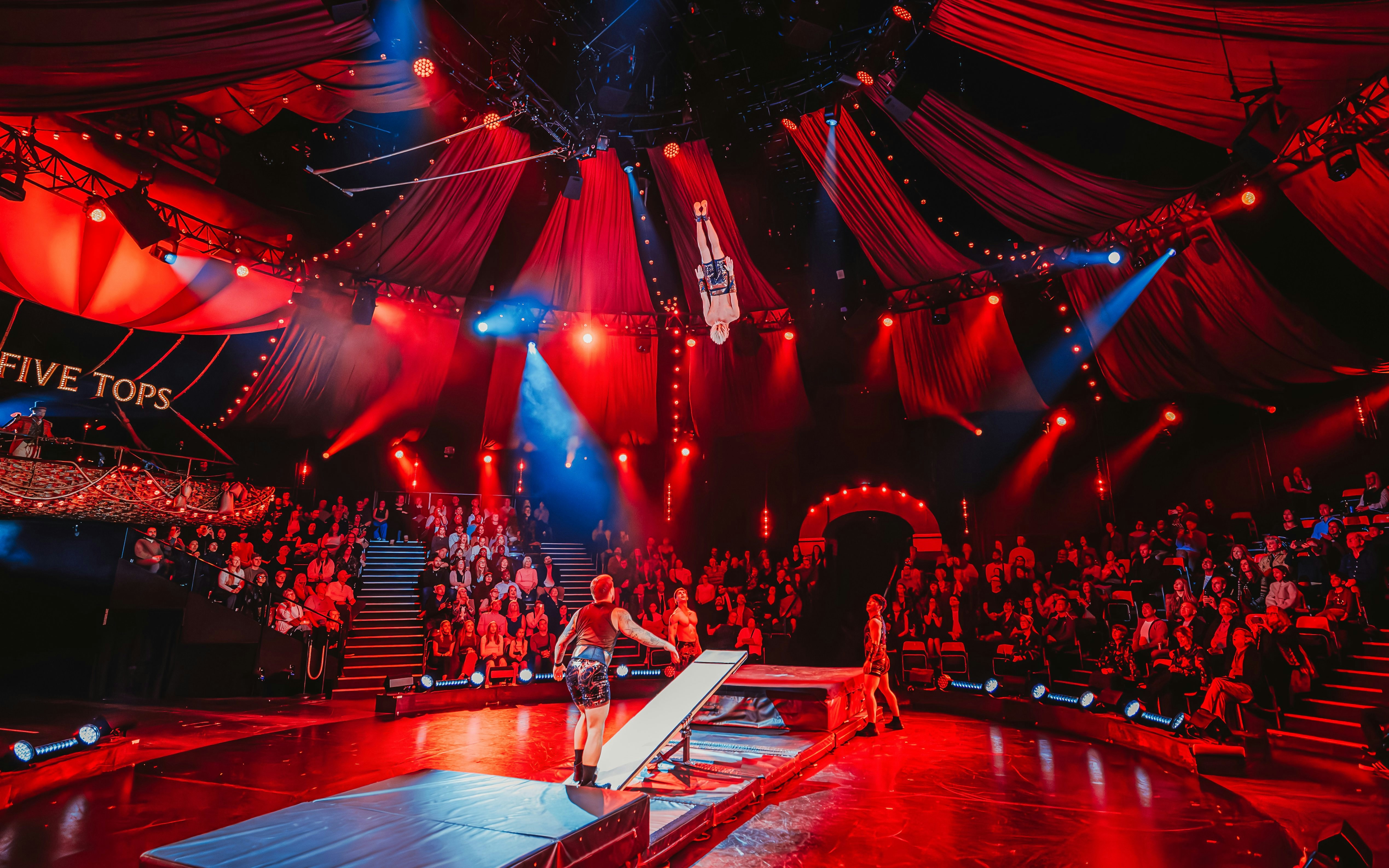 Acrobat performing mid-air flip during Come Alive Westend stage show.