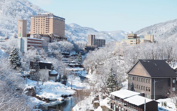 Jozankei Onsen buildings surrounded by snowy landscape and mountains.