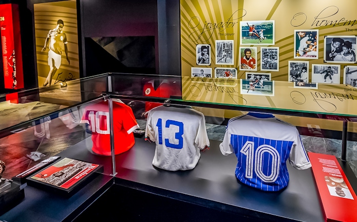 Benfica Stadium museum display with historic football jerseys and player photos.