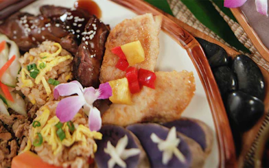 Traditional Hawaiian luau plate with grilled meat, rice, and tropical garnishes at Smiths Family Garden Luau.