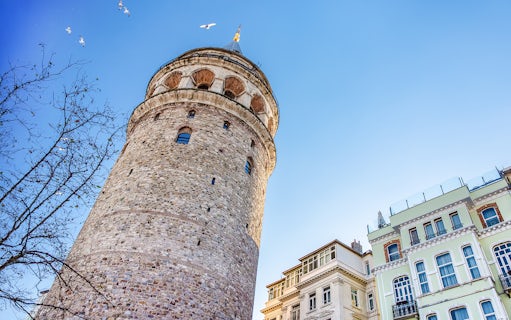 Galata Tower exterior with nearby buildings in Istanbul under a clear blue sky.