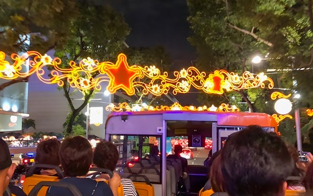 Open-top bus tour under festive Christmas lights in Singapore.