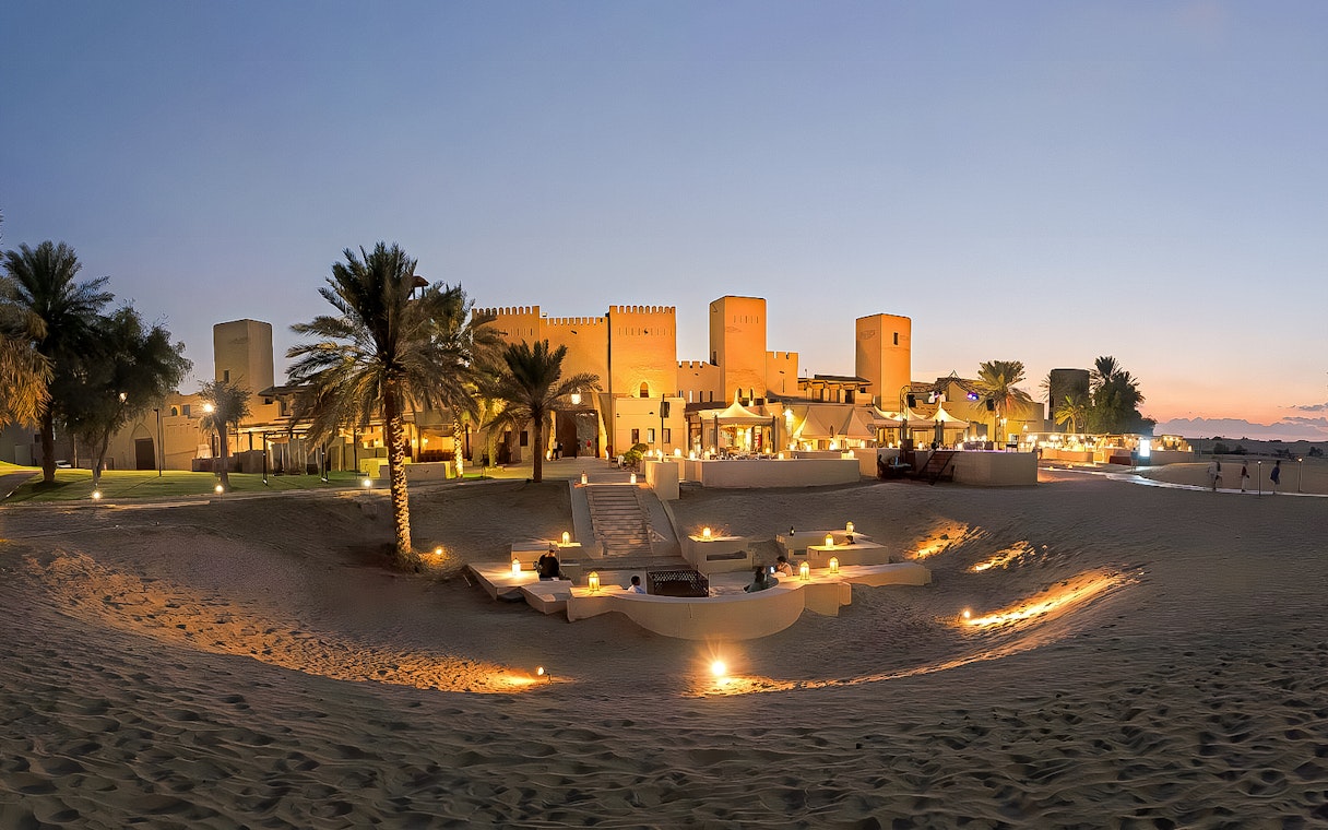 Panoramic view of a lit desert dining area at sunset, Dubai.
