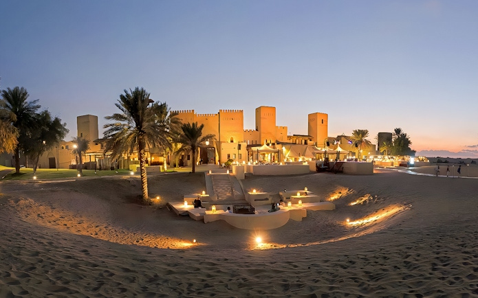 Panoramic view of a lit desert dining area at sunset, Dubai.
