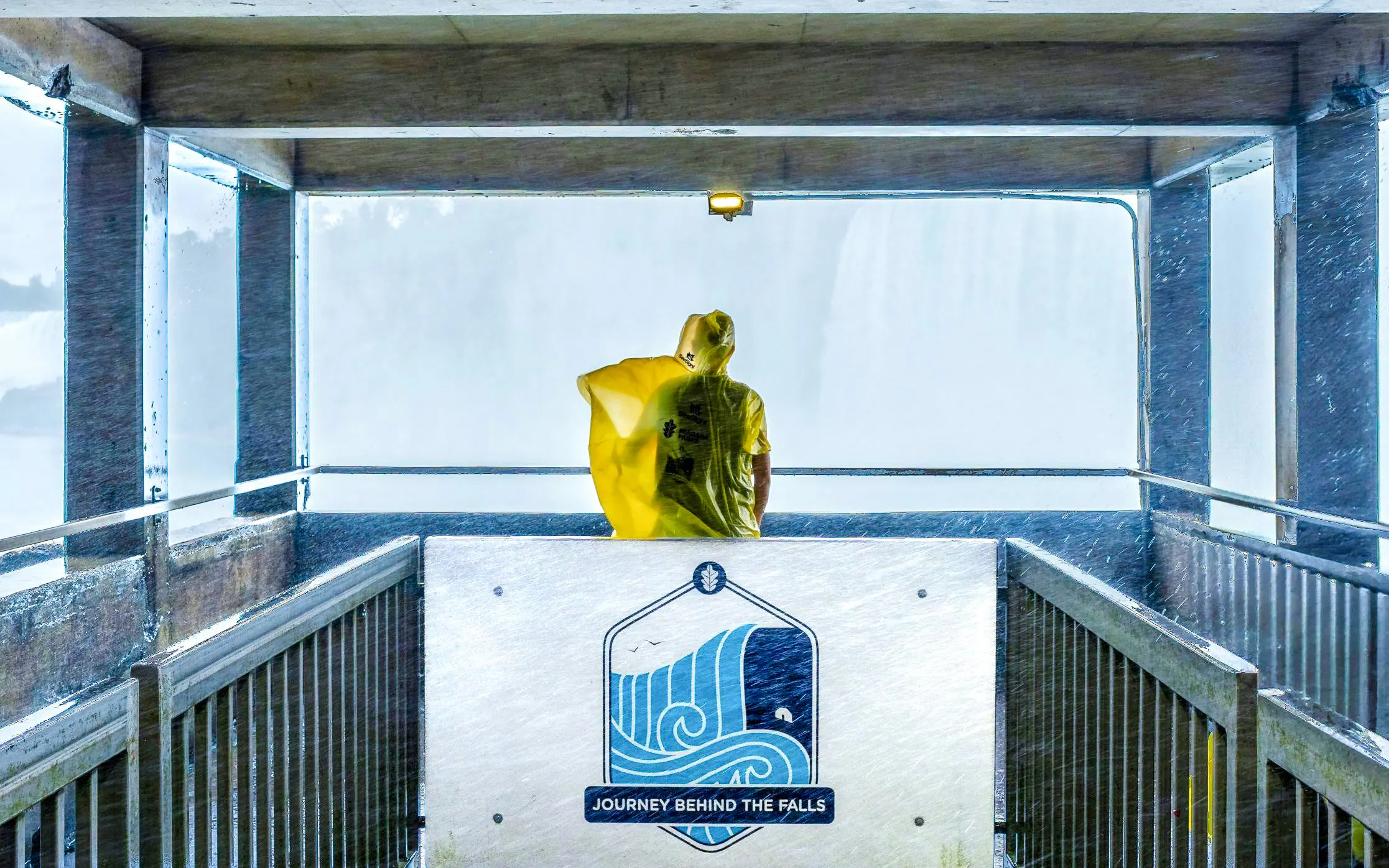 Visitor in yellow poncho at Journey Behind the Falls platform, Niagara Falls, Canada.