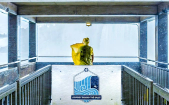 Visitor in yellow poncho at Journey Behind the Falls platform, Niagara Falls, Canada.