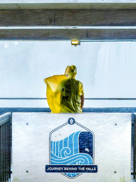 Visitor in yellow poncho at Journey Behind the Falls platform, Niagara Falls, Canada.