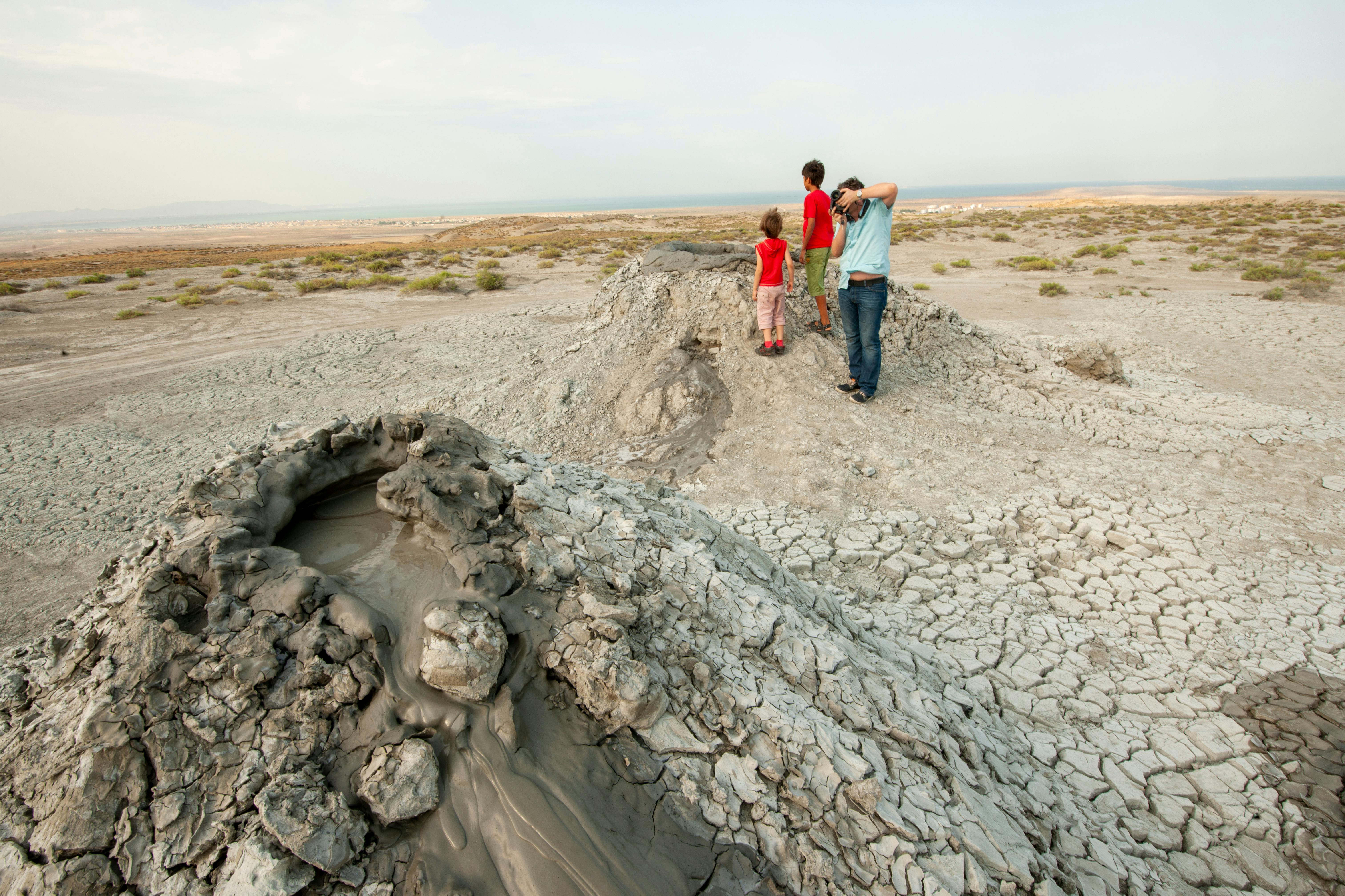 Mud volcanoes in Gobustan Reserve, Azerbaijan with tourists observing the landscape.