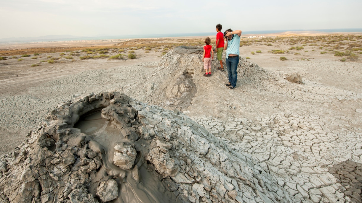 Mud volcanoes in Gobustan Reserve, Azerbaijan with tourists observing the landscape.