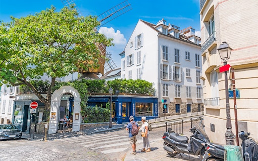 Street view of Montmartre, Paris with a historic windmill and tourists exploring.