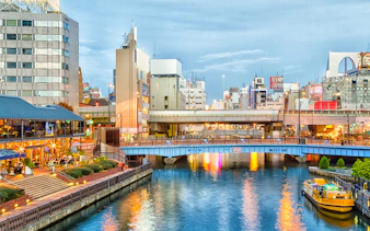 Dotonbori canal with illuminated buildings and a yellow boat in Osaka, Japan.
