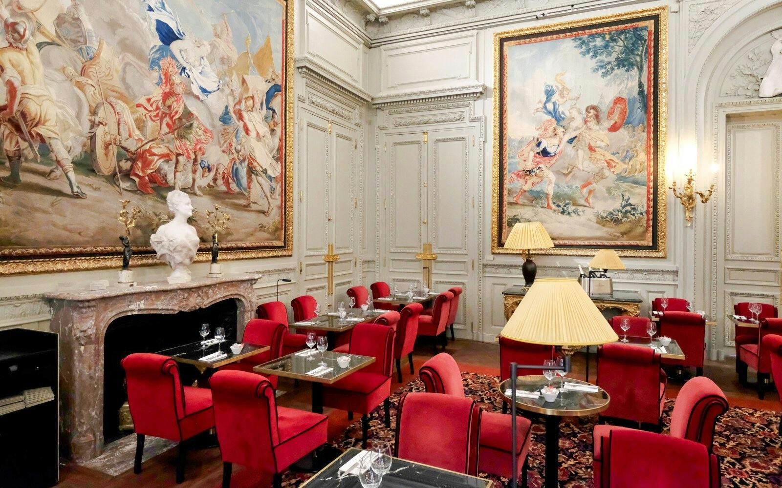 Jacquemart André Museum interior with red chairs, ornate tapestries, and marble fireplace.