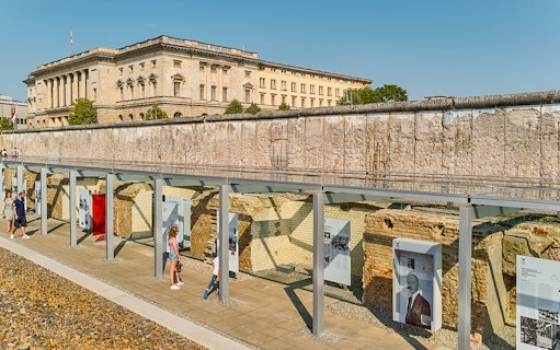 Berlin Wall exhibit with historical panels and visitors, showcasing stories of fate, love, and heroes.