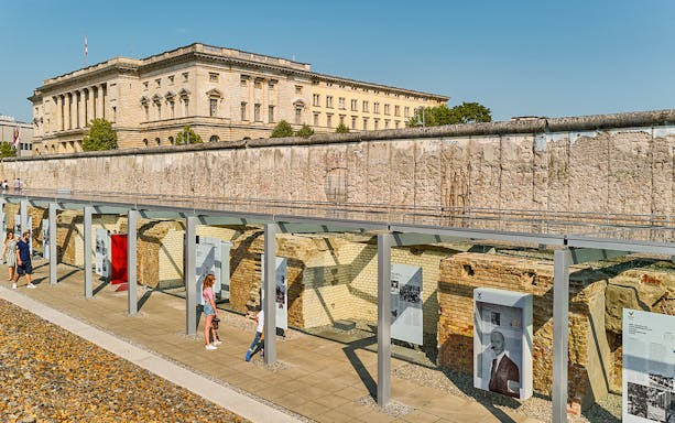 Berlin Wall exhibit with historical panels and visitors, showcasing stories of fate, love, and heroes.