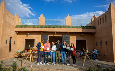 Group holding certificates outside a traditional Marrakesh building after a sunrise hot air balloon flight.