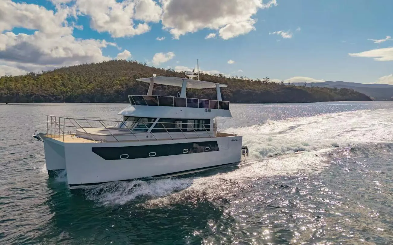 Cruise boat on Hobart waters with scenic coastline in background.