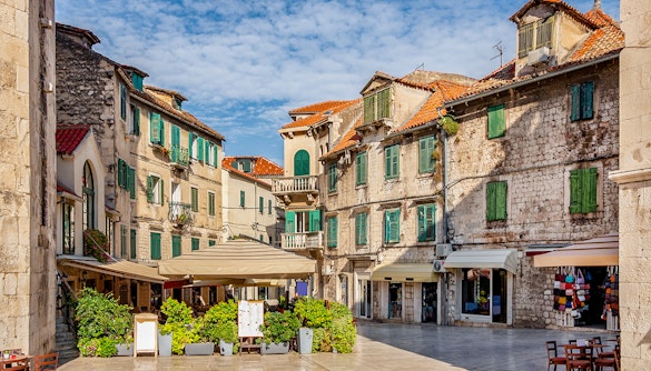 Historic square with stone buildings and green shutters in Split, Croatia.