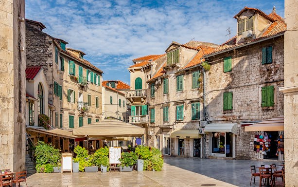 Historic square with stone buildings and green shutters in Split, Croatia.