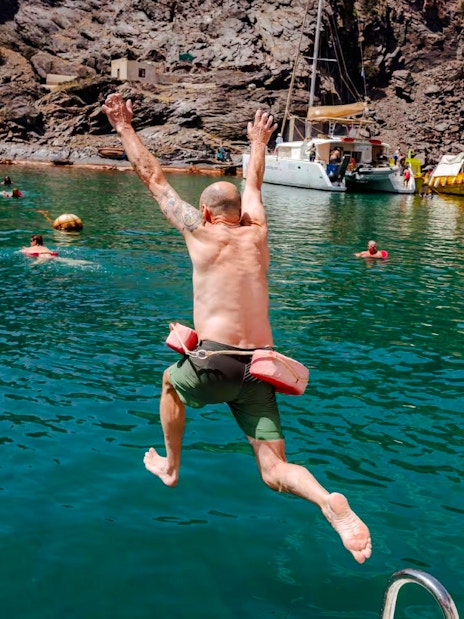 Guests swimming and jumping into the sea during Classic Catamaran Cruise tour.