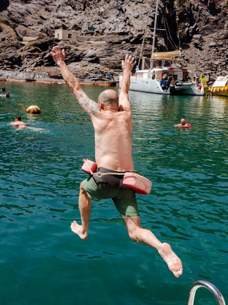 Guests swimming and jumping into the sea during Classic Catamaran Cruise tour.