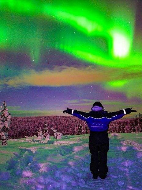 Guests viewing Northern Lights in snowy Rovaniemi landscape.