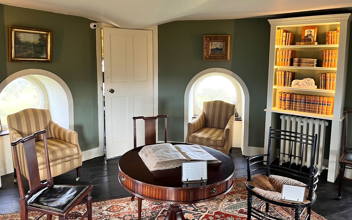 Interior of Broadway Tower with vintage furniture and bookshelves, Cotswolds tour from London.